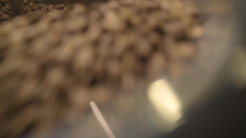 Coffee beans being stirred in a machine mixer