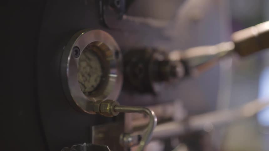 Ingredients turn and tumble seen through a round window in brewing equipment