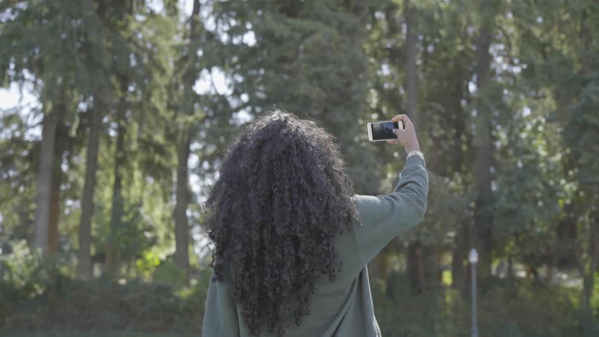 A woman takes a picture of a forest