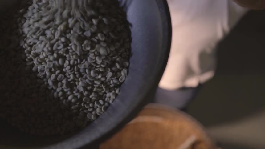 A person pours black seeds into a bowl