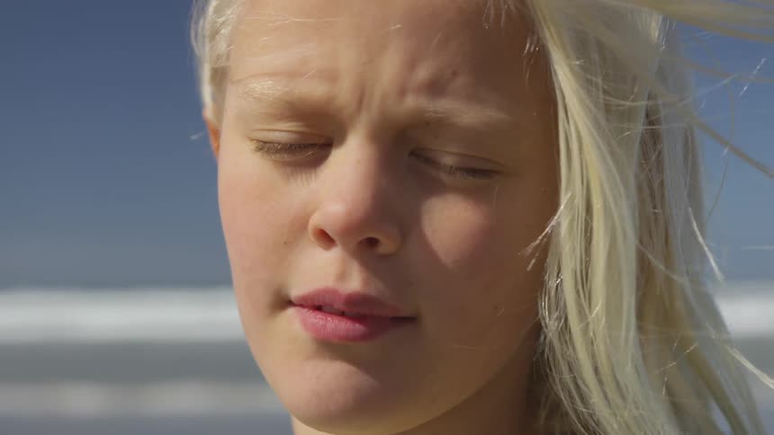 A white blonde female child standing in the wind with her eyes closed
