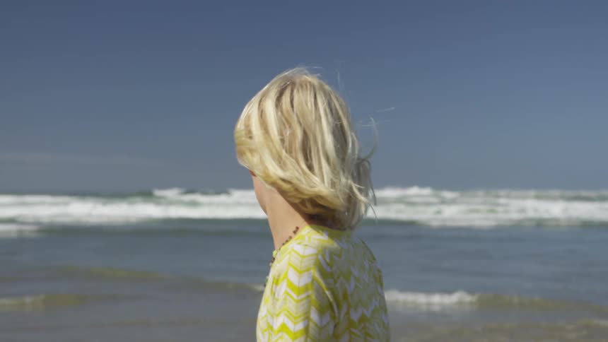 Blonde girl walks along beach