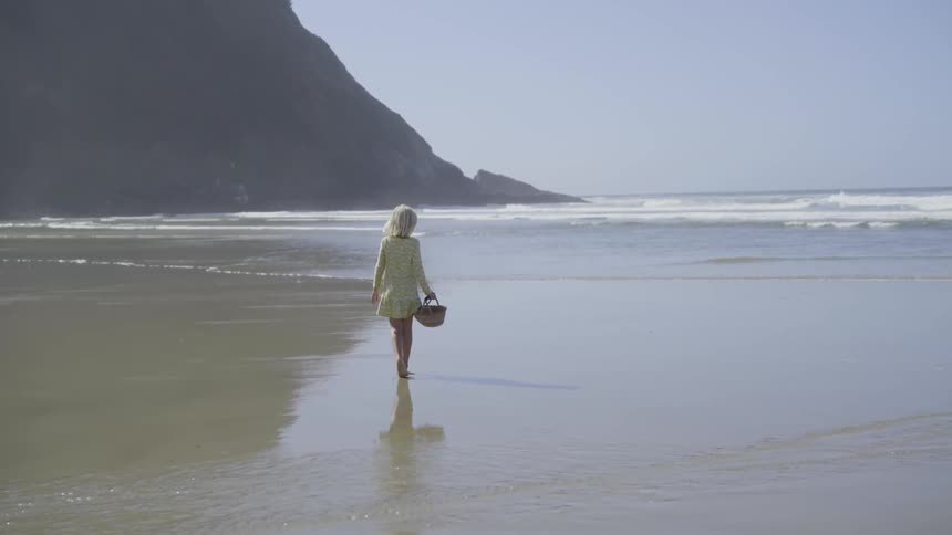 A child walks along the beach carrying a basket