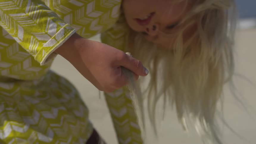 A girl on the beach playing with sand