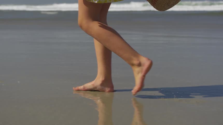 Female in dress walks along beach