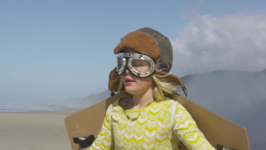 A girl is an airplane costume runs through the sand