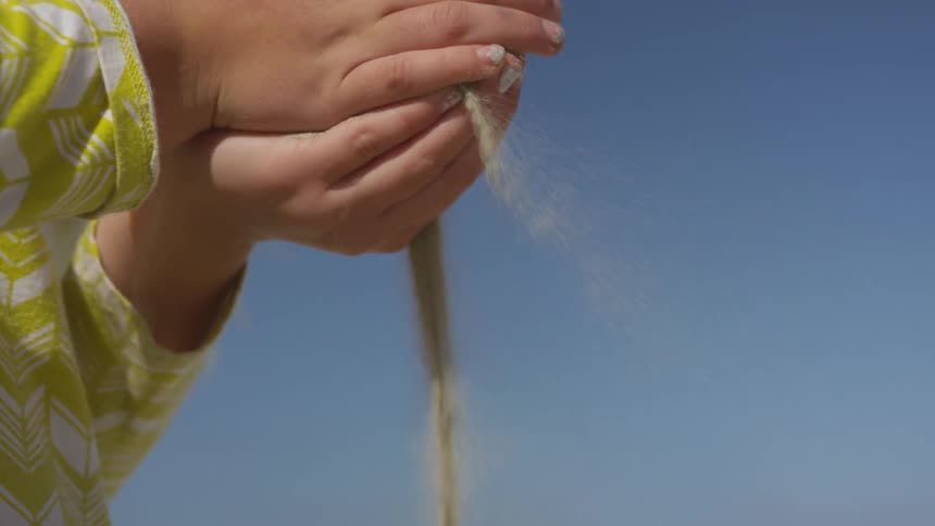 Sand runs between girls clasped hands
