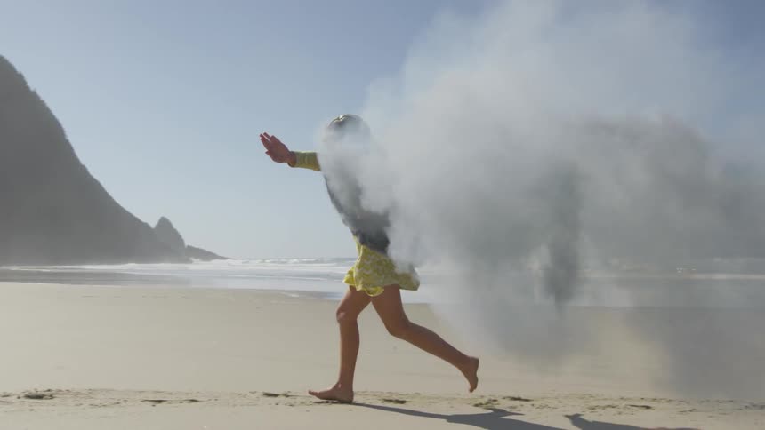A child runs on the beach wearing smoking wings
