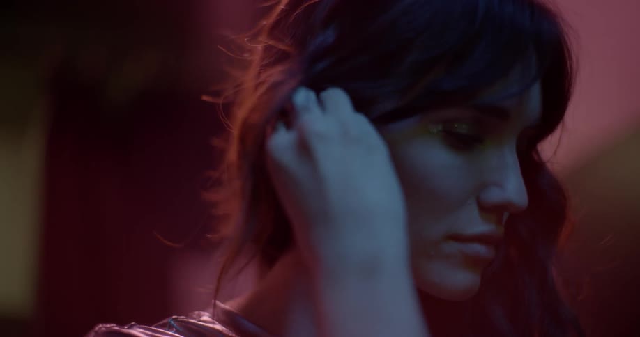 A woman is adjusting an ear piece indoors