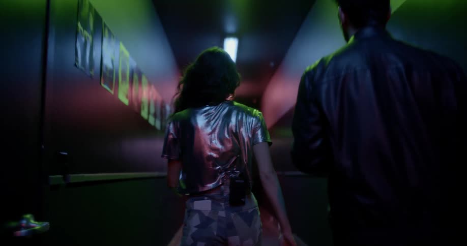 A woman and man are walking in a dark room