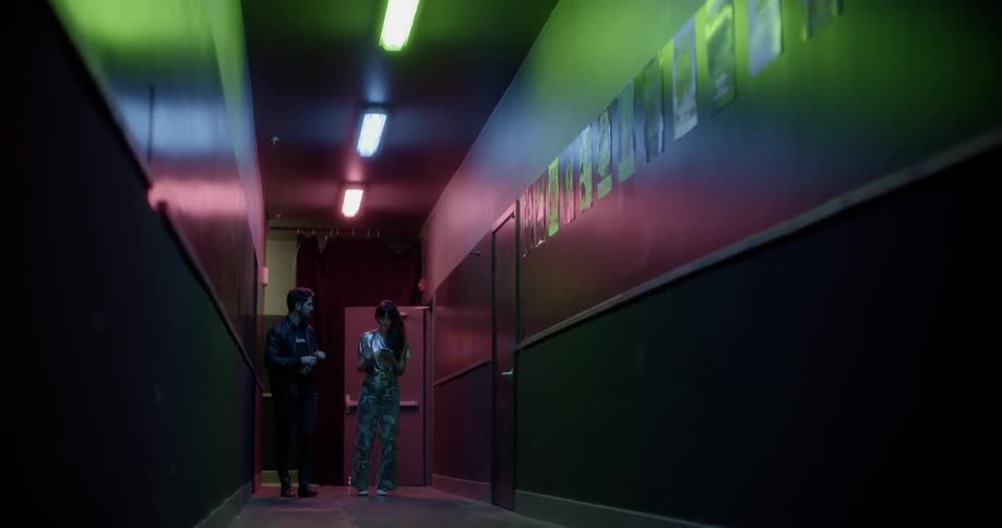 A man and a woman walk down a hallway