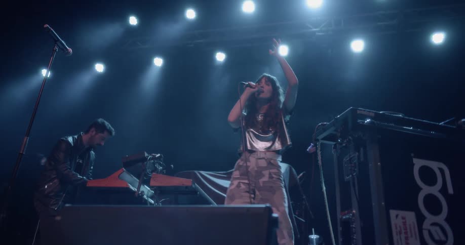 A woman sings on a stage with a man playing keyboard