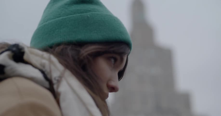 A woman adjusts her hat in the city