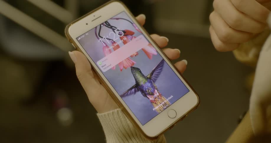 A womans hands holding a cell phone face up to see the home screen and notifications