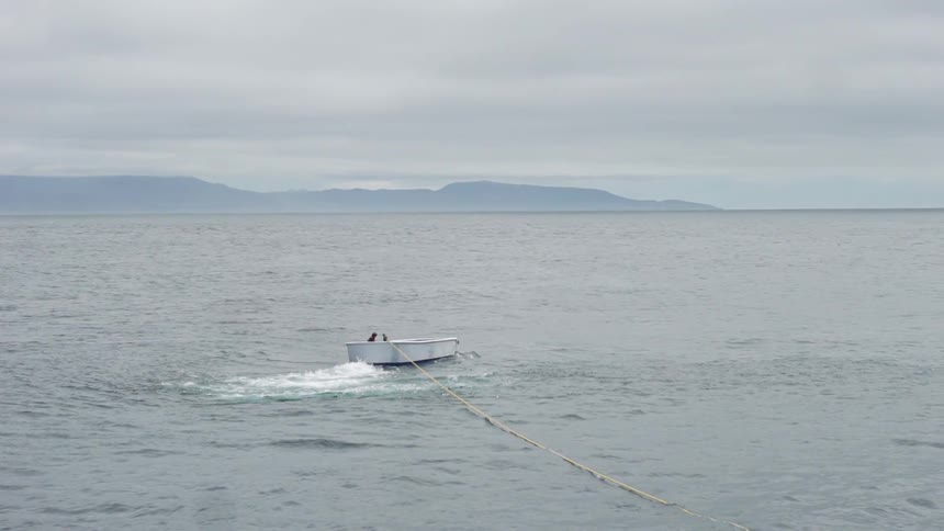 A boat floats on a mountain lake on a cloudy day
