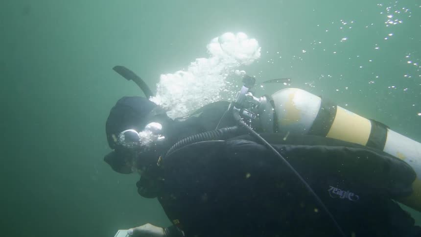 A deep sea diver exhales bubbles while swimming in an ocean