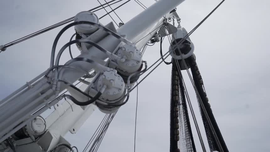 A net hangs from a white mast on a ship