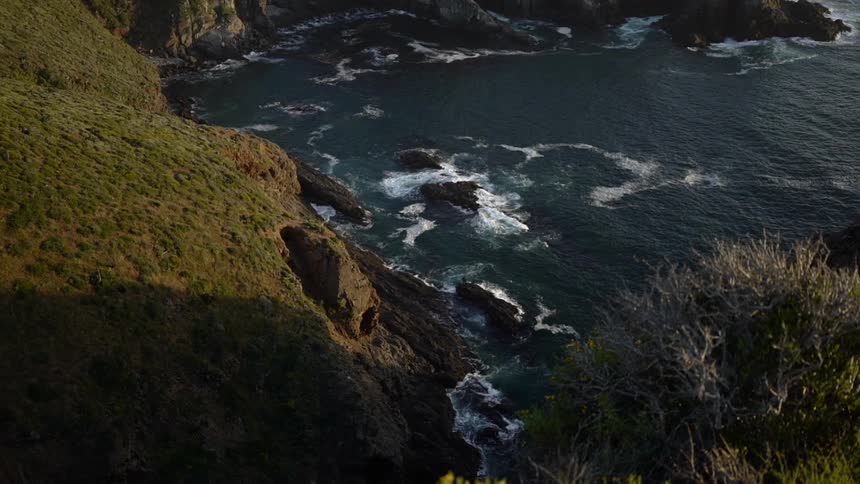 Ocean waves splash against rocks near shore in a cove