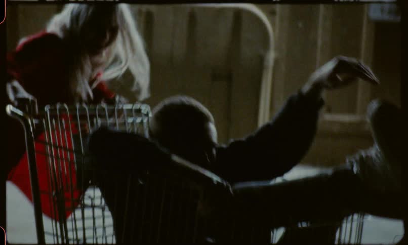 Teenage girls spinning and pushing a teenage boy in a shopping cart