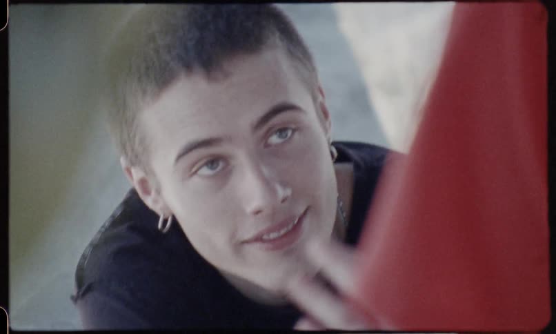 A man with pierced ears smiles while talking and nodding his head