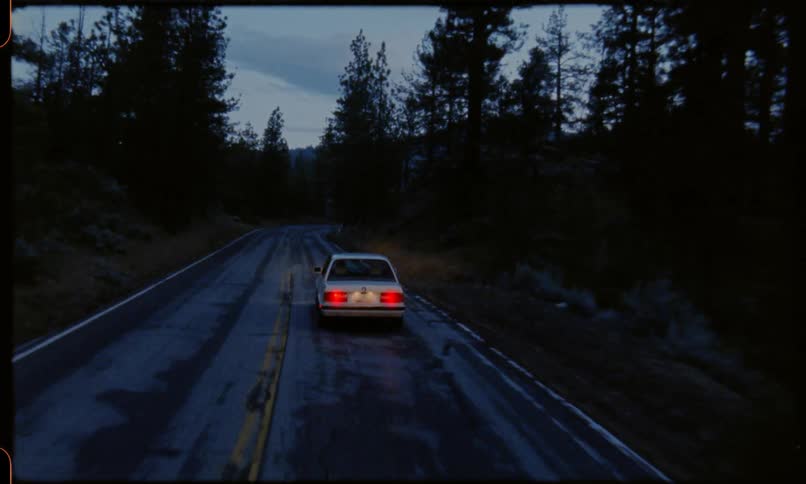 A car travels on a forest road in mountains at night