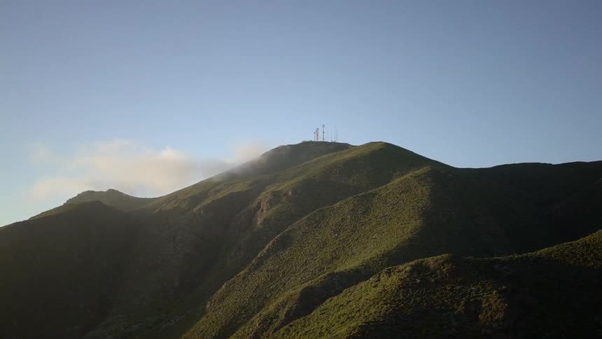 Clouds float near hills covered in green vegetation
