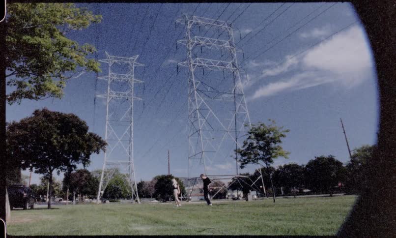 Two young people hold onto one another and spin in a circle underneath power lines on a sunny day