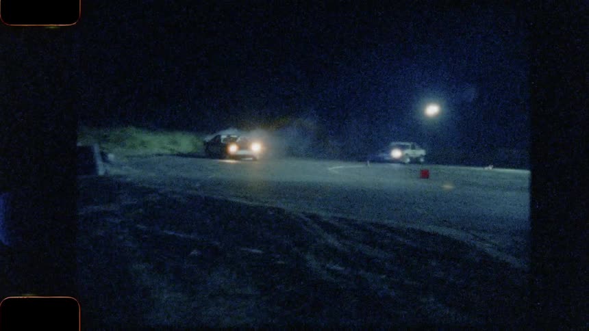 Cars drifting around corners on a racing course at night
