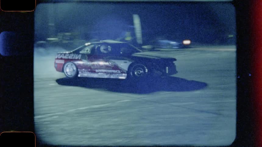 Driver oversteers while maintaining control and driving the race car through the track at night