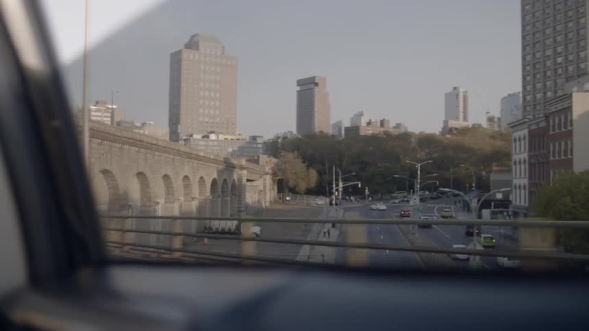 A car travel along a bridge in a city during the day