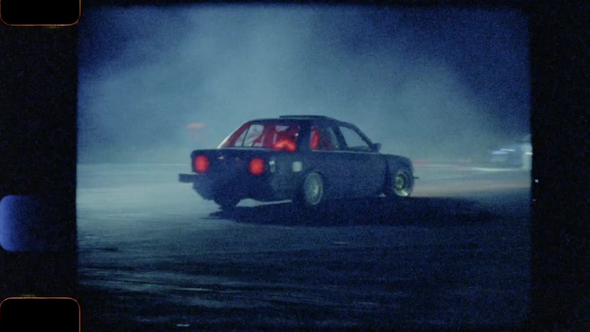 The cars are drifting as they race in a circle at night