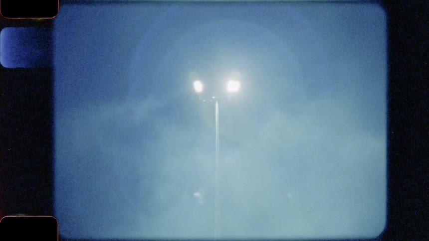 Smoke flies through the air under a light
