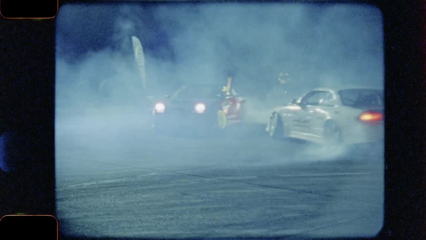 Two vehicles are drifting in a circle in a street battle