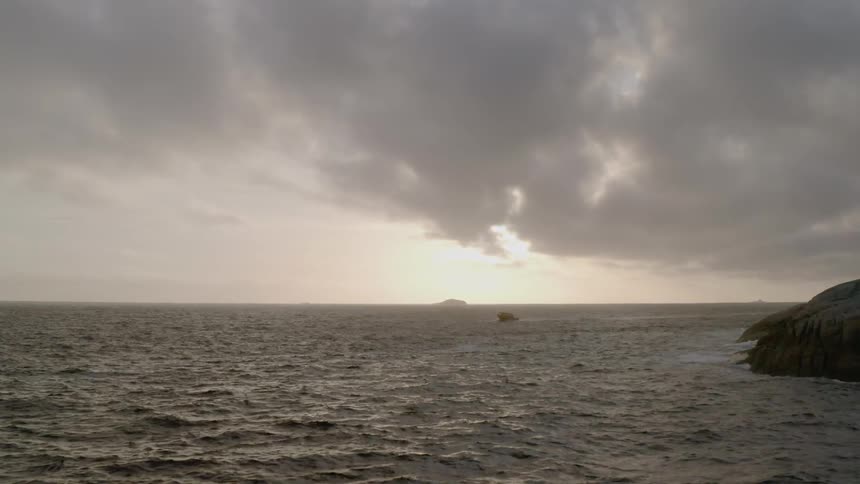 The ocean just off the coast of land mass on a cloudy day