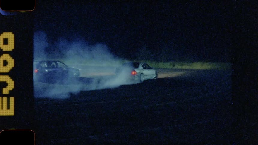 Cars racing and drifting on the track under the lights at night