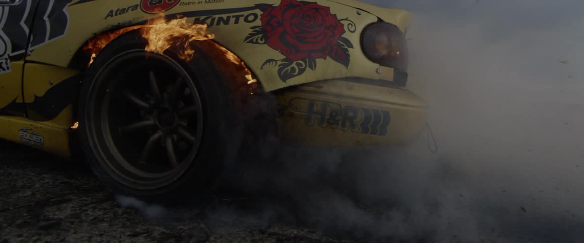 A car drift racing with its back tire on fire