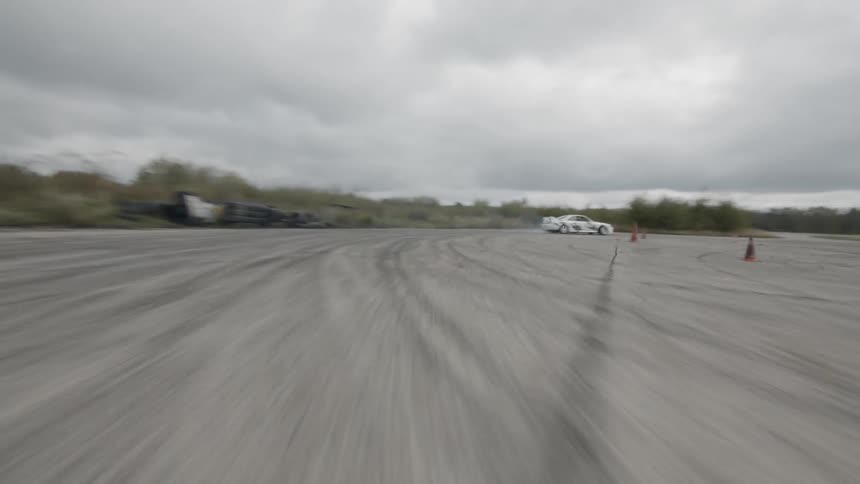A race car skids while speeding over a dirt road on a cloudy day