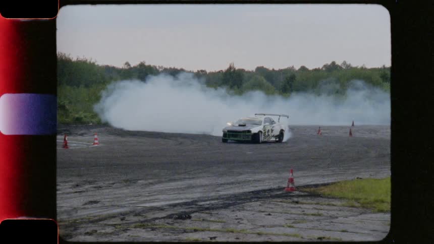Race cars navigating an s curve in a racing track with smoking wheels