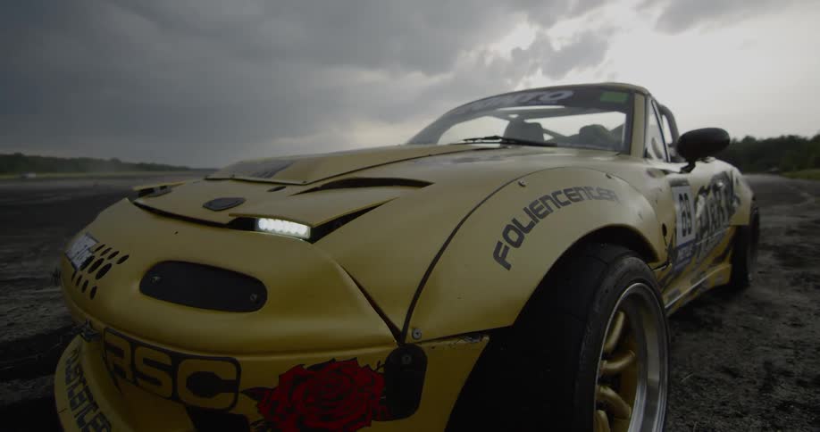 A yellow racing car sits in a rural area