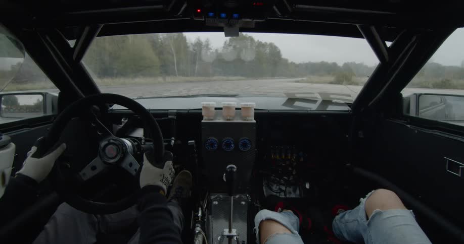 Two people are racing in a lot spinning around in a car