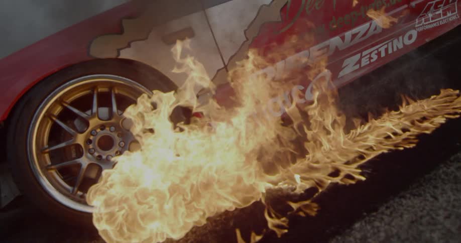 A fire burns on the ground next to a red race car