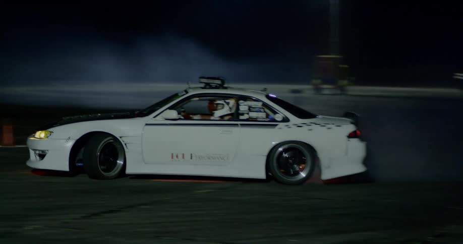 A car is speeding at night drifting on a dirt track