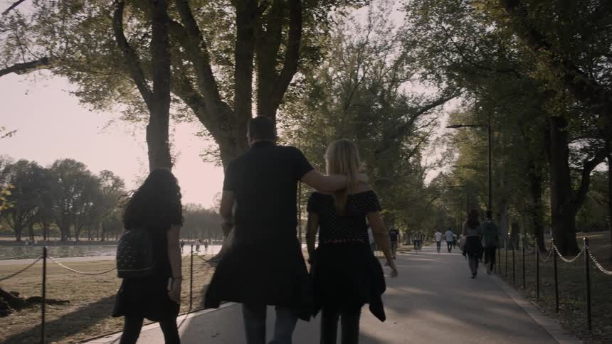 People walk down a wide path in a park