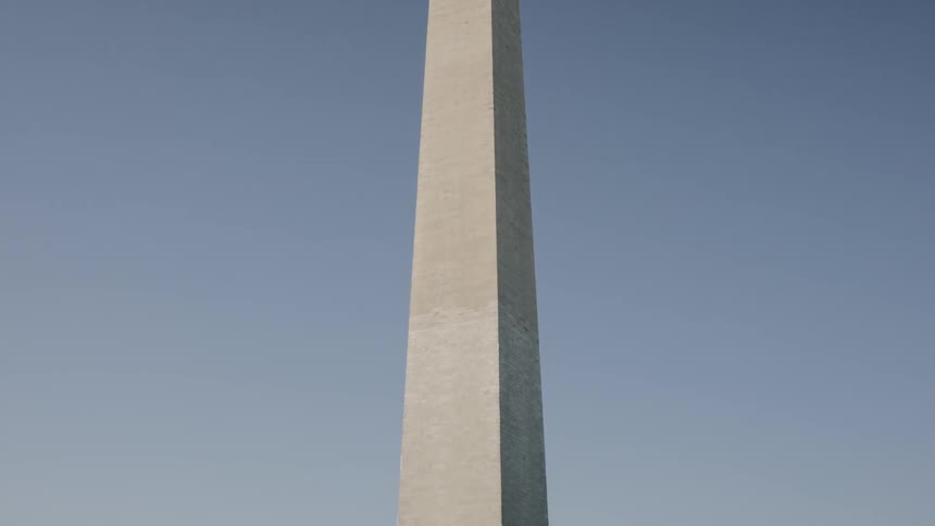 The washington monument surrounded by flags as people walk by