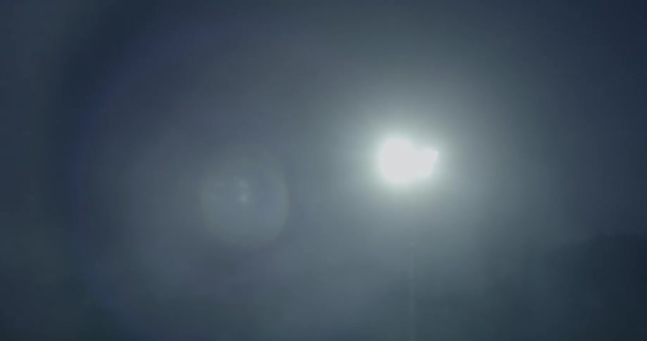 A spotlight shining through the fog at nighttime