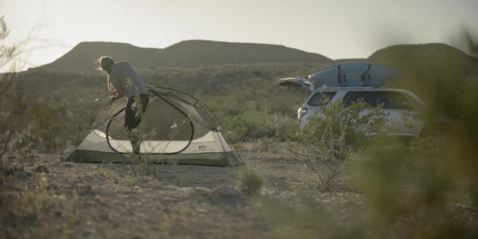 A woman sets up a tent in the desert