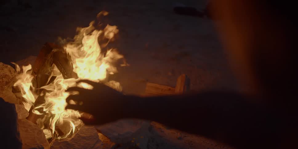 A person holds their hand out to a fire