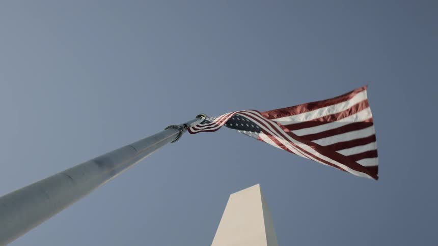An american flag flies in front of a monument