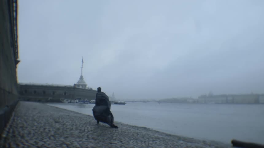 A man runs next to a river in a long cloak