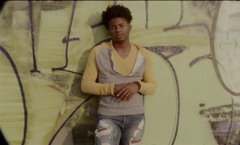 A tight shot of a person in front of a wall of graffiti
